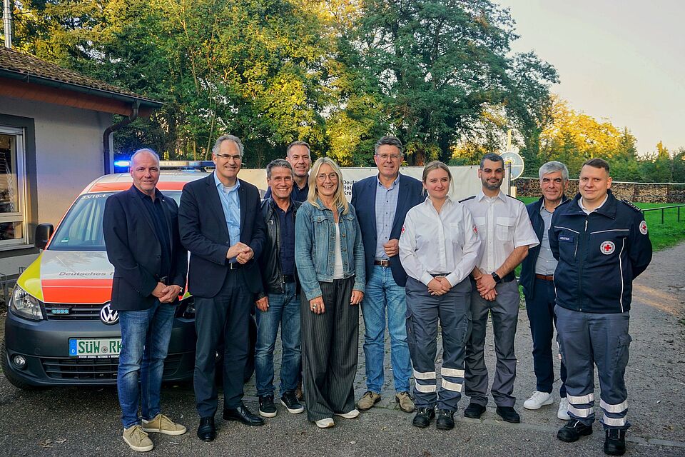 Viele Menschen stehen vor einem Einsatzfahrzeug des DRK